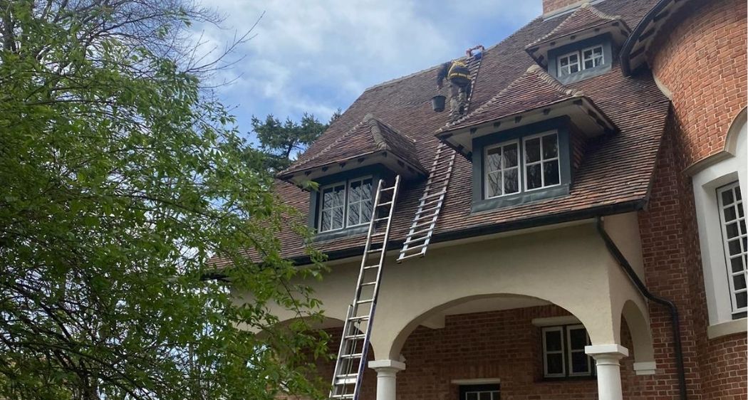 Travaux de toiture sur maison traditionnelle avec échelles